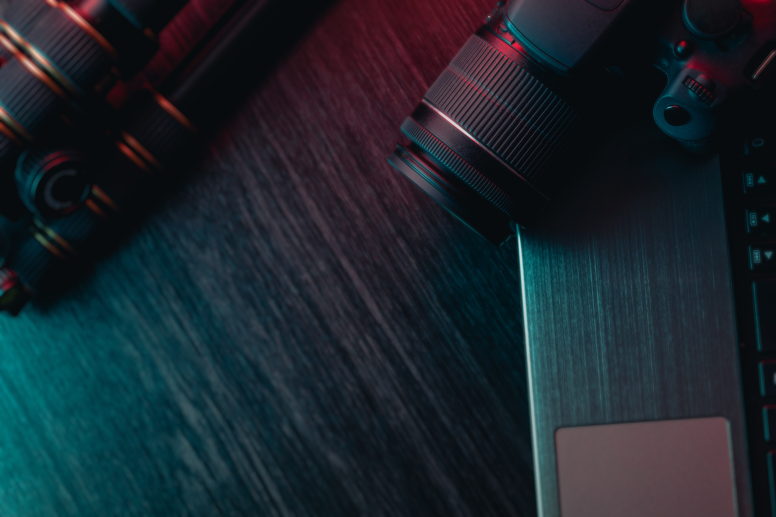A workspace with laptop, modern camera, lens and tripod on a wood table. Freelance or creative man or woman